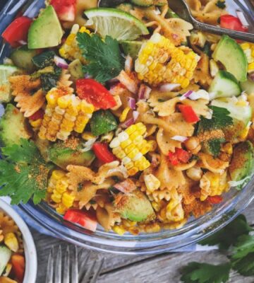 A colorful vegan southwest pasta salad full of corn on the cob, avocado, and other veggies