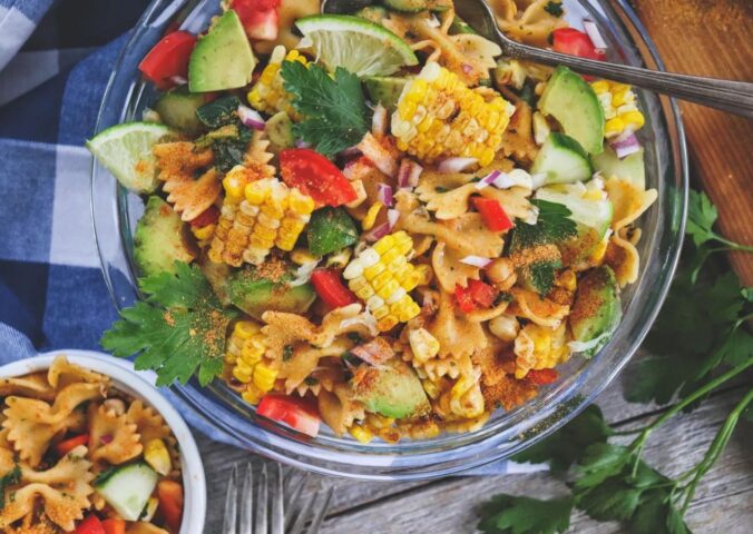 A colorful vegan southwest pasta salad full of corn on the cob, avocado, and other veggies