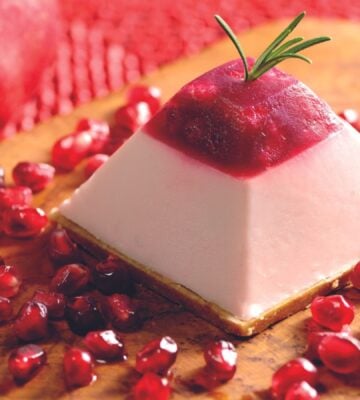 vegan pomegranate cheesecake made with a cheesecake base, pomegranate jelly, pomegranate seeds, and a pink and vegan cheesecake mix