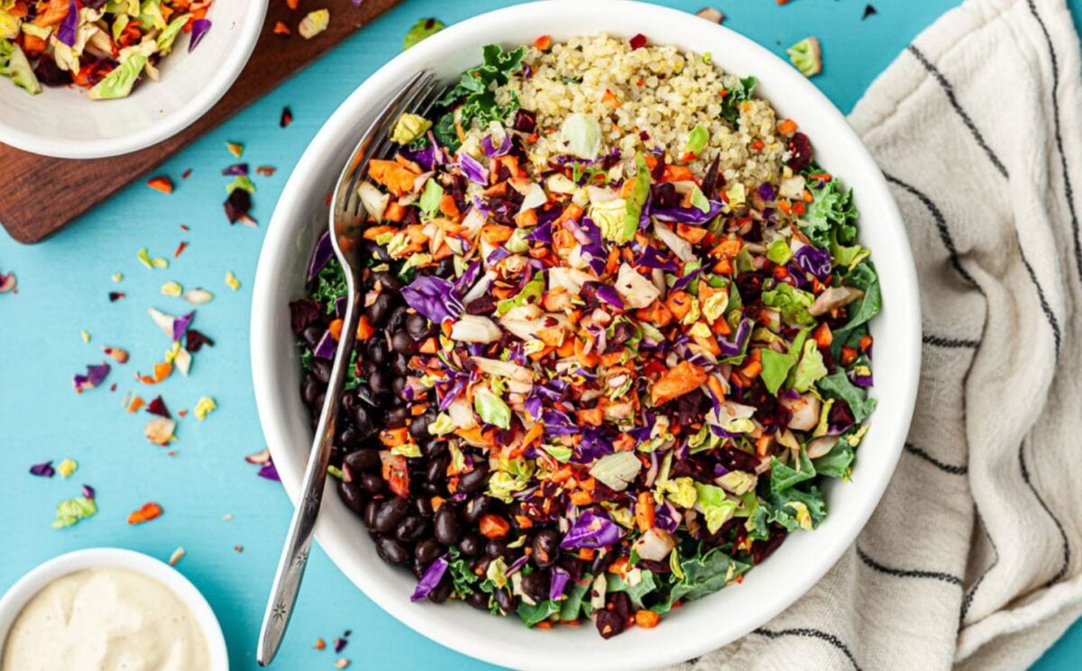 A bowl of brightly colored vegan salad made with a crunchy vegetable-based salad topping