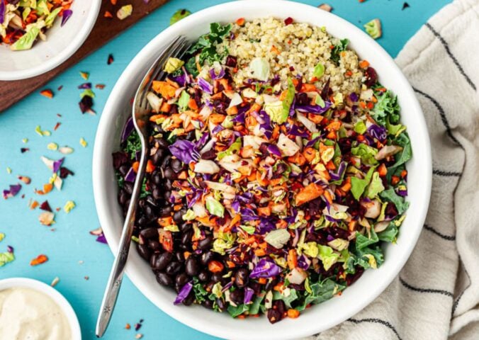 A bowl of brightly colored vegan salad made with a crunchy vegetable-based salad topping