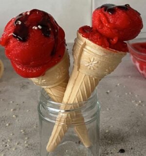 a picture of two ice cream cones topped with vegan 3-ingredient strawberry ice cream