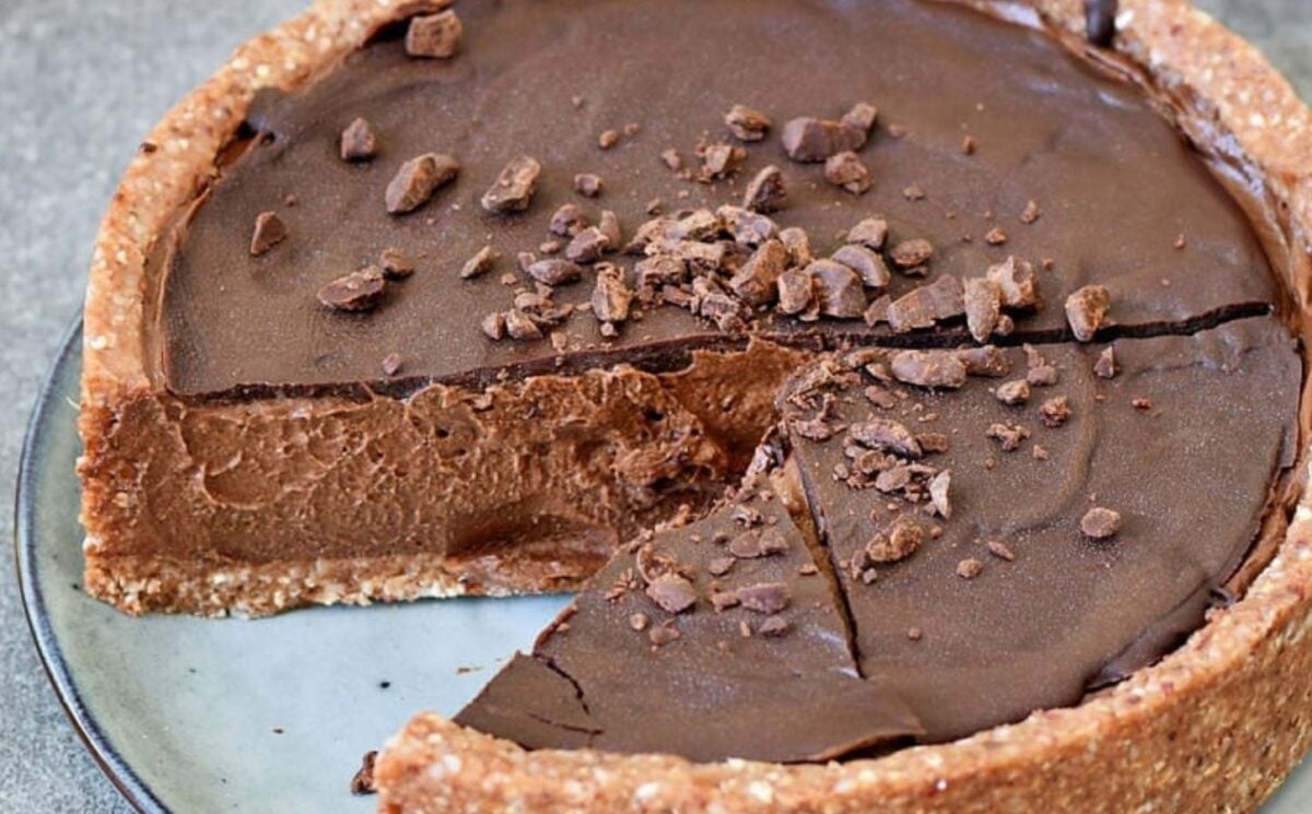 A picture of a dense vegan chocolate pie made with a thick nutty crust and a chocolate drizzle