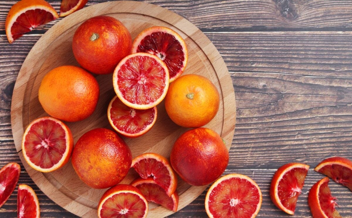 Photo shows a large bowl of brightly colored blood oranges - some whole, some halved, and some quartered