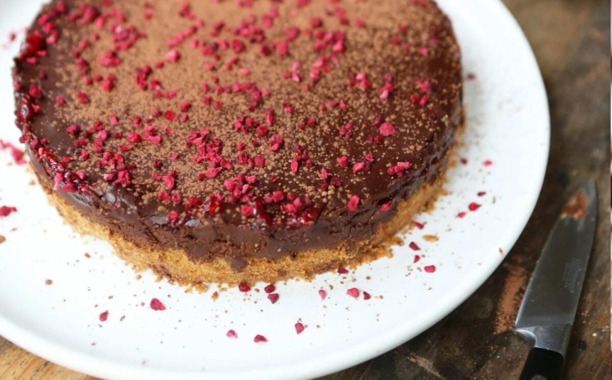 a vegan chocolate and raspberry torte made with a digestive base, a raspberry layer, and a deep chocolate torte filling