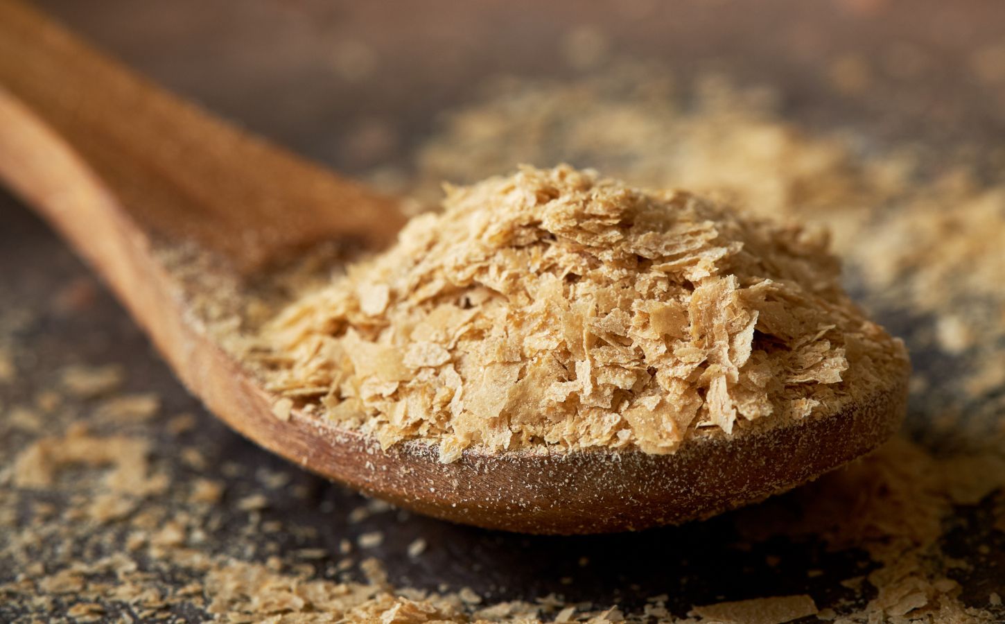 A wooden spoon full of nutritional yeast, a complete vegan protein source