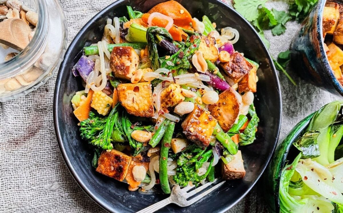 Photo shows a plate of vegan pad Thai featuring tofu and whole peanuts