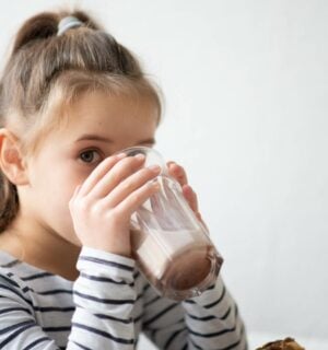 A child drinking a dairy-free protein shake in a kitchen
