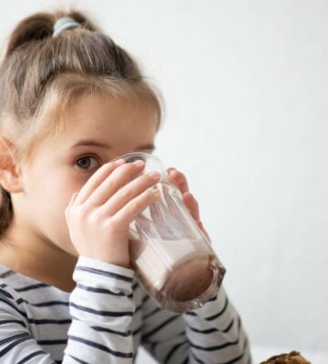 A child drinking a dairy-free protein shake in a kitchen
