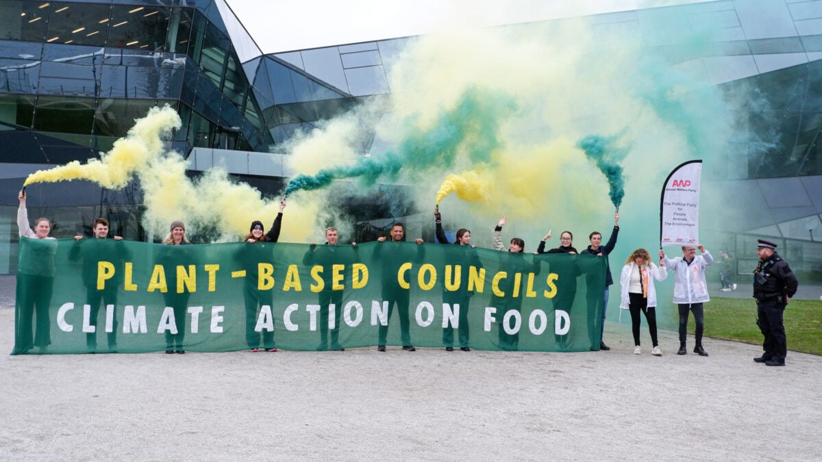 Photo shows a group of Plant Based Councils campaigners with a large banner and flares protesting in London