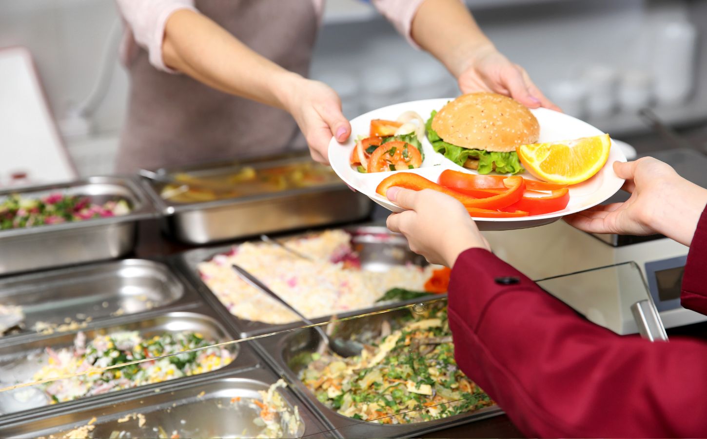 A school lunch worker handing a child a plant-based meal