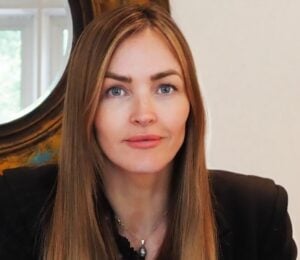 Photo shows Plant-Based Food Alliance CEO Marisa Heath sat at a wooden desk in front of a circular mirror