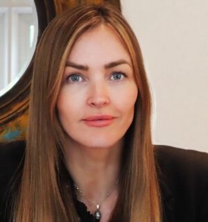 Photo shows Plant-Based Food Alliance CEO Marisa Heath sat at a wooden desk in front of a circular mirror