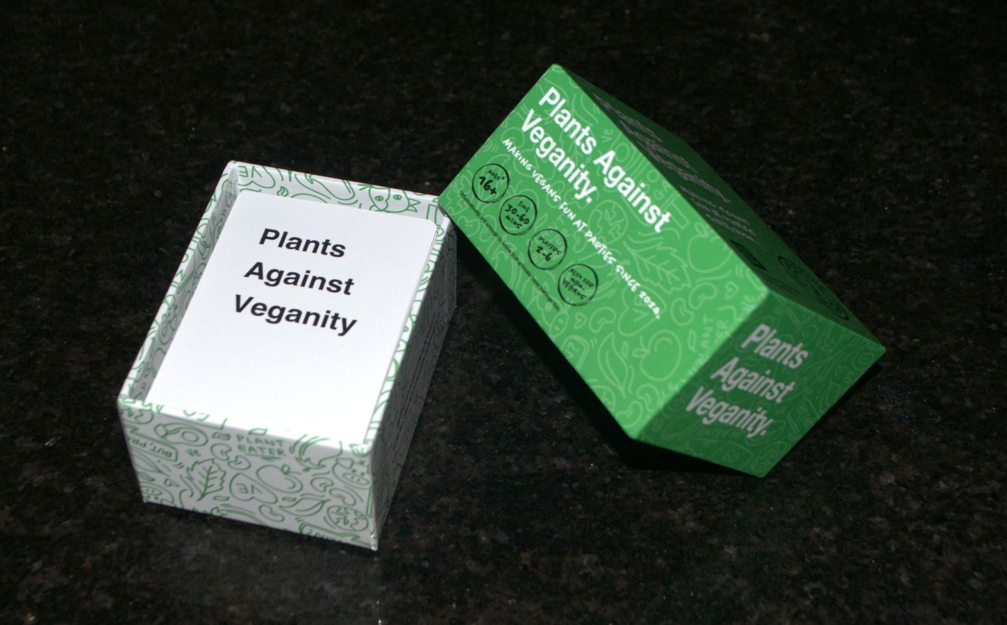 Photo shows the green and white box for This Is Not A Game's "Plants Against Veganity" vegan card game