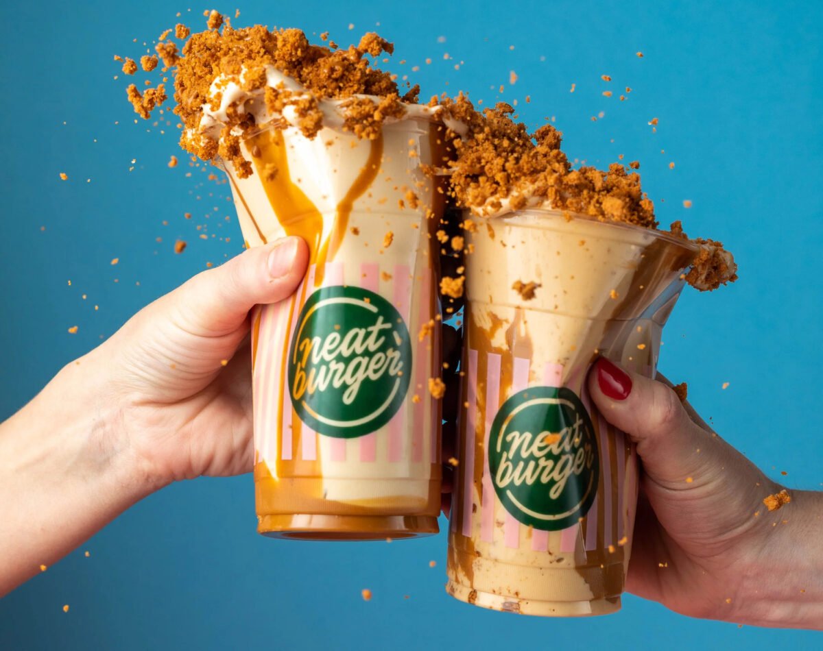 Photo shows two people raising Neat Burger vegan milkshakes made with Oatly soft serve ice cream