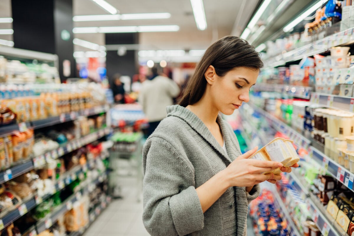 A woman reading the label of some vegan dairy products in the supermarket