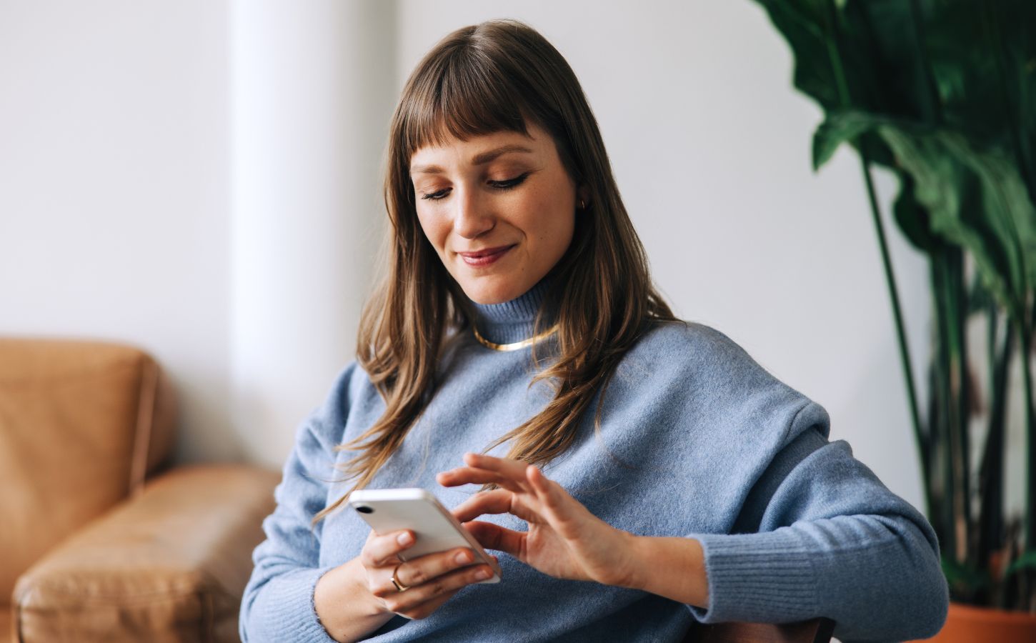 A woman looking at her phone while sitting on a sofa