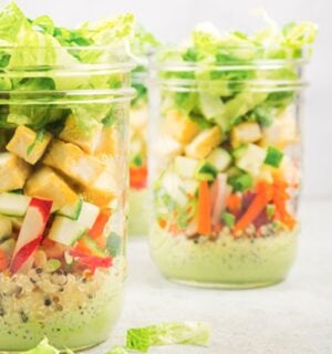 a picture of vegan bahn mi mason jar salads with quinoa, tofu, romaine lettuce, a tasty dressing, and radish