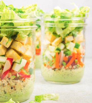 a picture of vegan bahn mi mason jar salads with quinoa, tofu, romaine lettuce, a tasty dressing, and radish