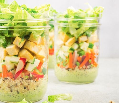 a picture of vegan bahn mi mason jar salads with quinoa, tofu, romaine lettuce, a tasty dressing, and radish