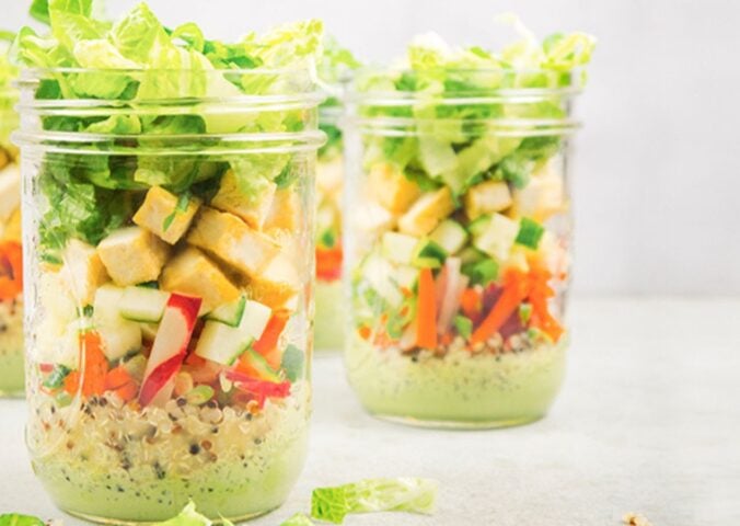 a picture of vegan bahn mi mason jar salads with quinoa, tofu, romaine lettuce, a tasty dressing, and radish