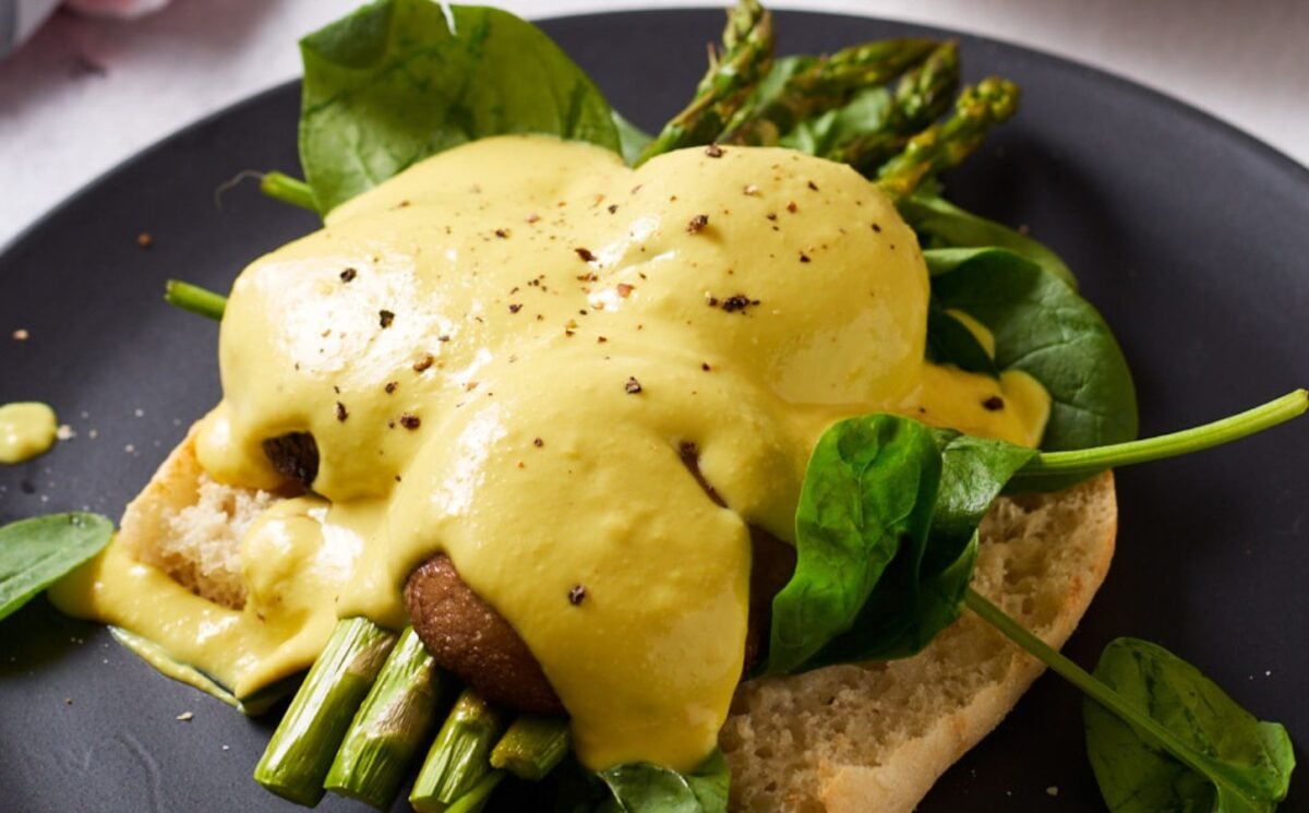 a picture of a mushroom benedict with hollandaise sauce with asparagus, spinach, silken tofu, and other ingredients