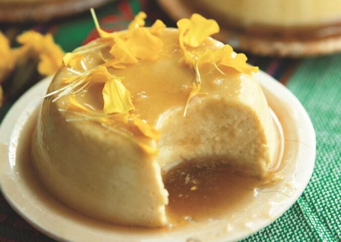 a picture of a vegan coconut flan made with tofu, coconut milk and cream, agar powder, sugar, vanilla, and topped with a syrup and edible flowers