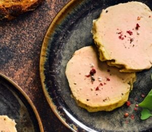 Photo shows a portion of Gourmey's cultivated meat foie gras plated up with some salad leaves