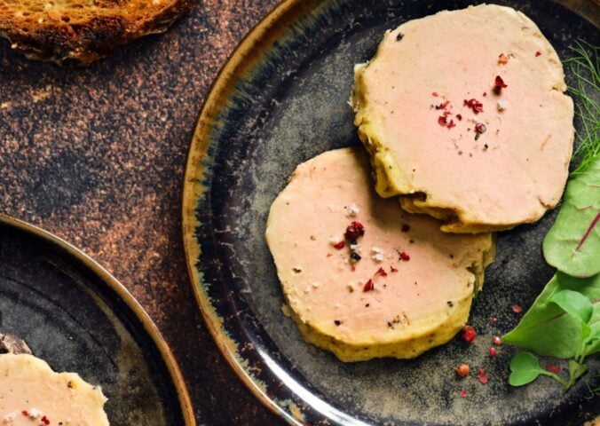 Photo shows a portion of Gourmey's cultivated meat foie gras plated up with some salad leaves