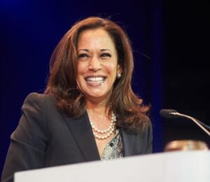 Democratic presidential nominee Kamala Harris standing at a podium and smiling