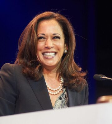 Democratic presidential nominee Kamala Harris standing at a podium and smiling