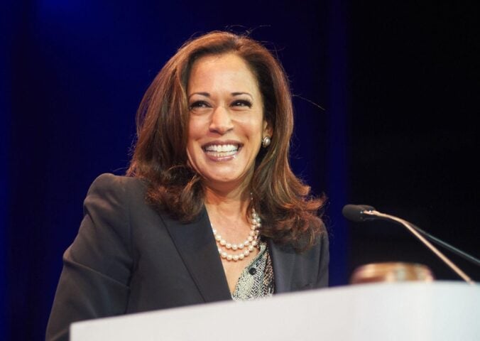 Democratic presidential nominee Kamala Harris standing at a podium and smiling