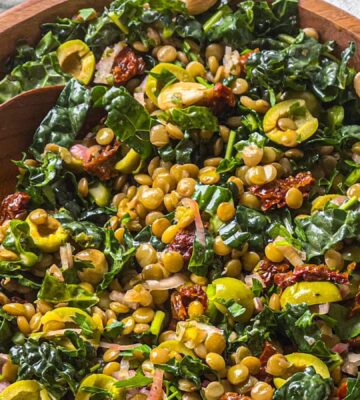 a picture of a lemon and pesto lentil salad made with olives, sundried tomatoes, kale, and almonds