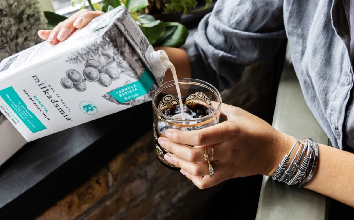 Photo shows someone pouring Milkadamia macadamia milk into a cup of coffee. The brand's new product is "2D printed" oat milk.