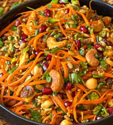 a picture of a moroccan carrot salad with citrust turmeric dressing made with chickpeas, cashews, orange juice, and more