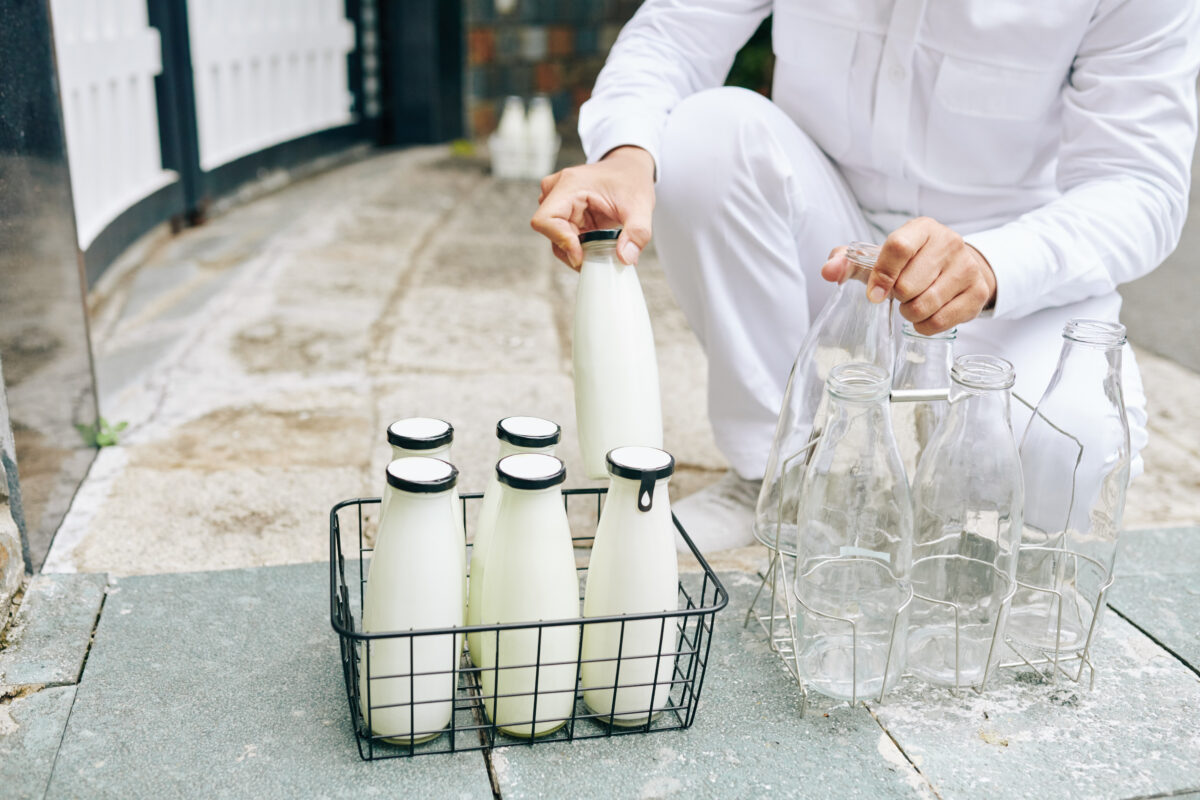 A milkman delivers milk to a house