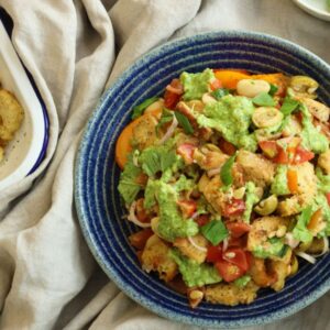 a picture of a panzanella pasta salad with croutons, tomato, onion, and plant-based feta