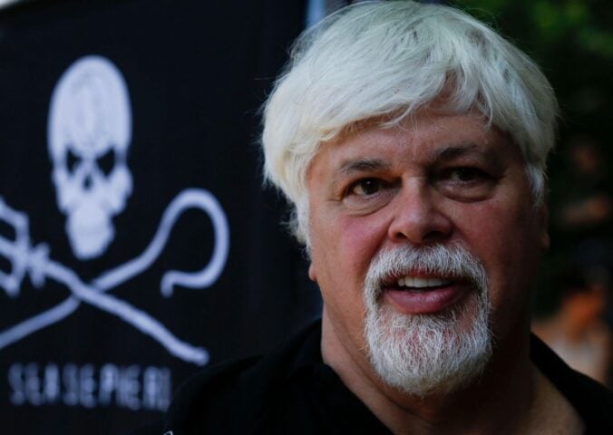 Photo shows anti-whaling activist Paul Watson standing in front of a Sea Shepherd flag