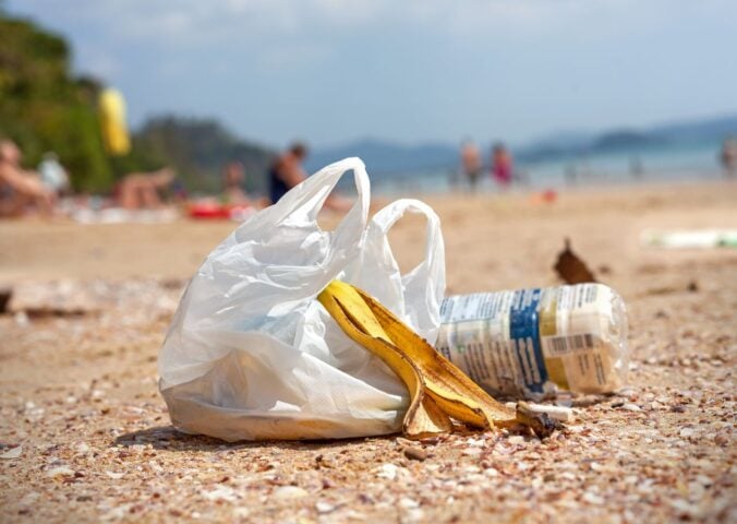 Plastic bag on a beach next to a banana skin and plastic bottle