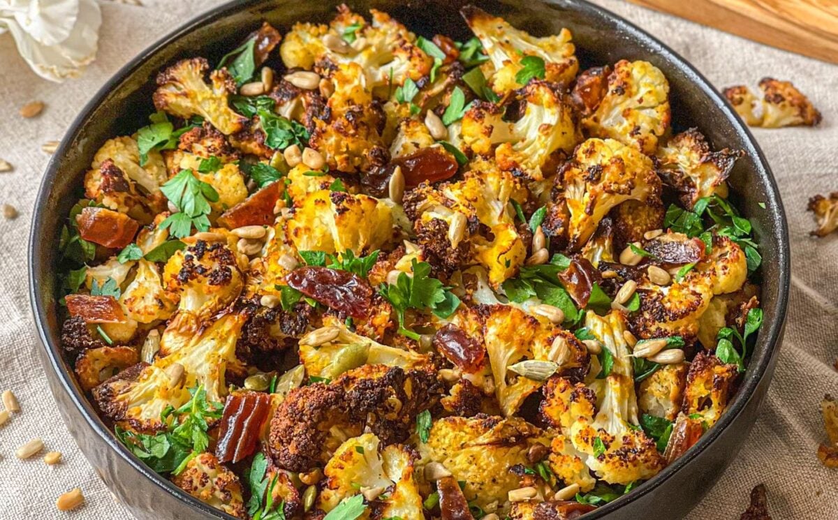 a picture of a bowl of roasted cauliflower salad with dates and tahini served with sunflower seeds