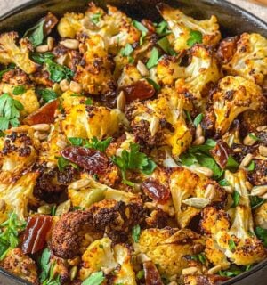 a picture of a bowl of roasted cauliflower salad with dates and tahini served with sunflower seeds