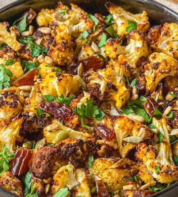 a picture of a bowl of roasted cauliflower salad with dates and tahini served with sunflower seeds