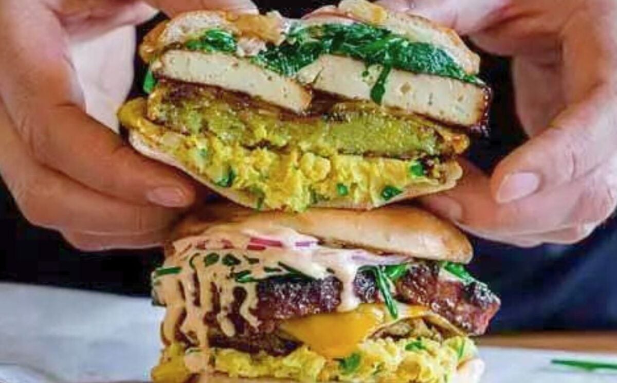 a picture of two smokey tofu breakfast sandwiches made with hashbrowns, chickpea 'egg' salad, and tasty slabs of seasoned tofu