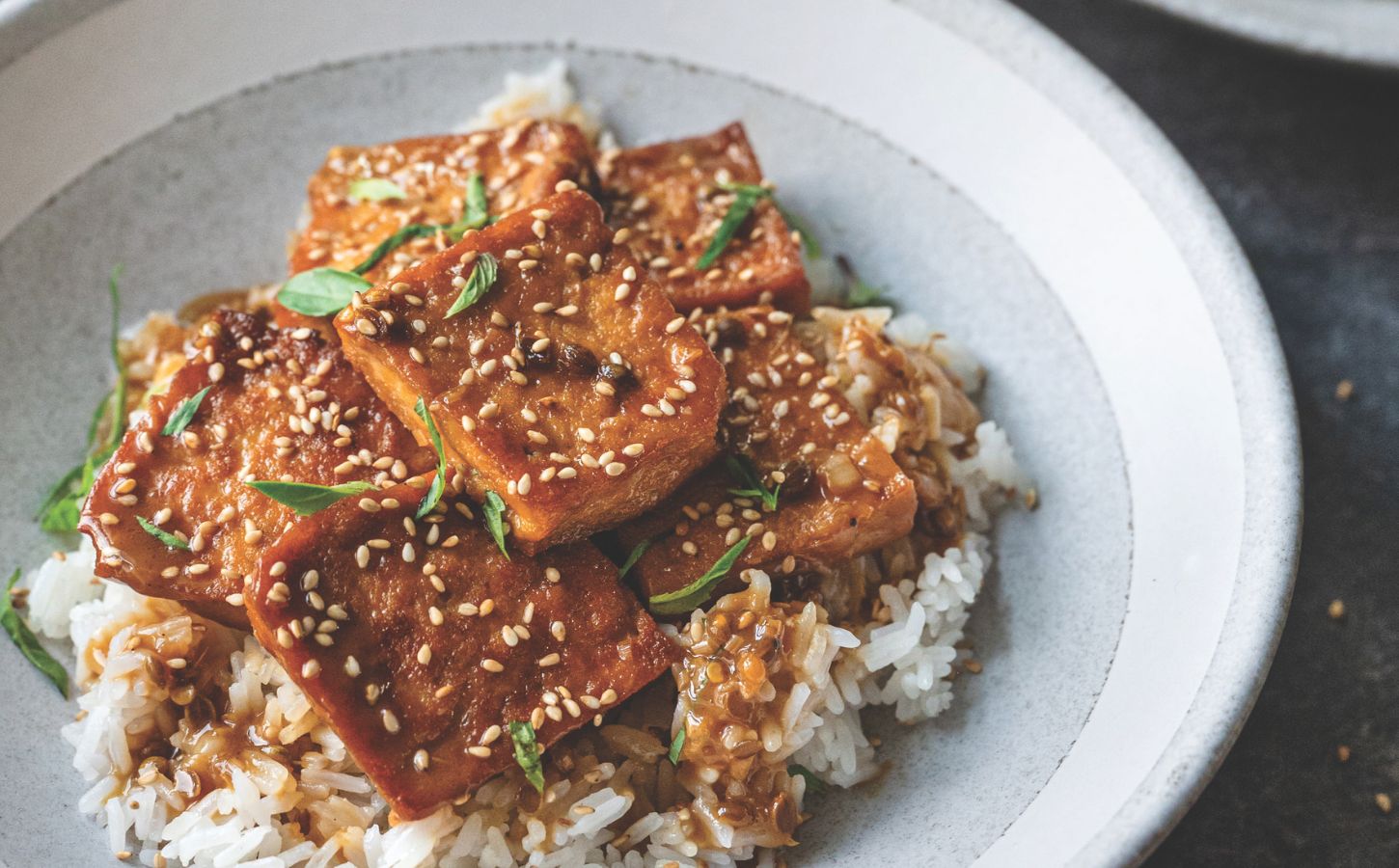 a picture of sticky coconut milk braised tofu on jasmine rice topped with Thai basil and sesame seeds