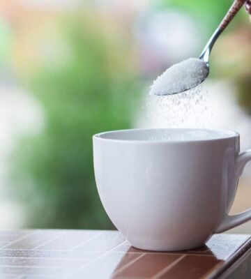 A person pouring sugar, which could be replaced in the future with sweet proteins, into a cup