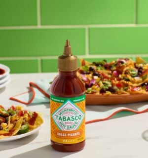 Photo shows a bottle of the new Tabasco hot sauce alongside plates of Mexican and Tex-Mex food