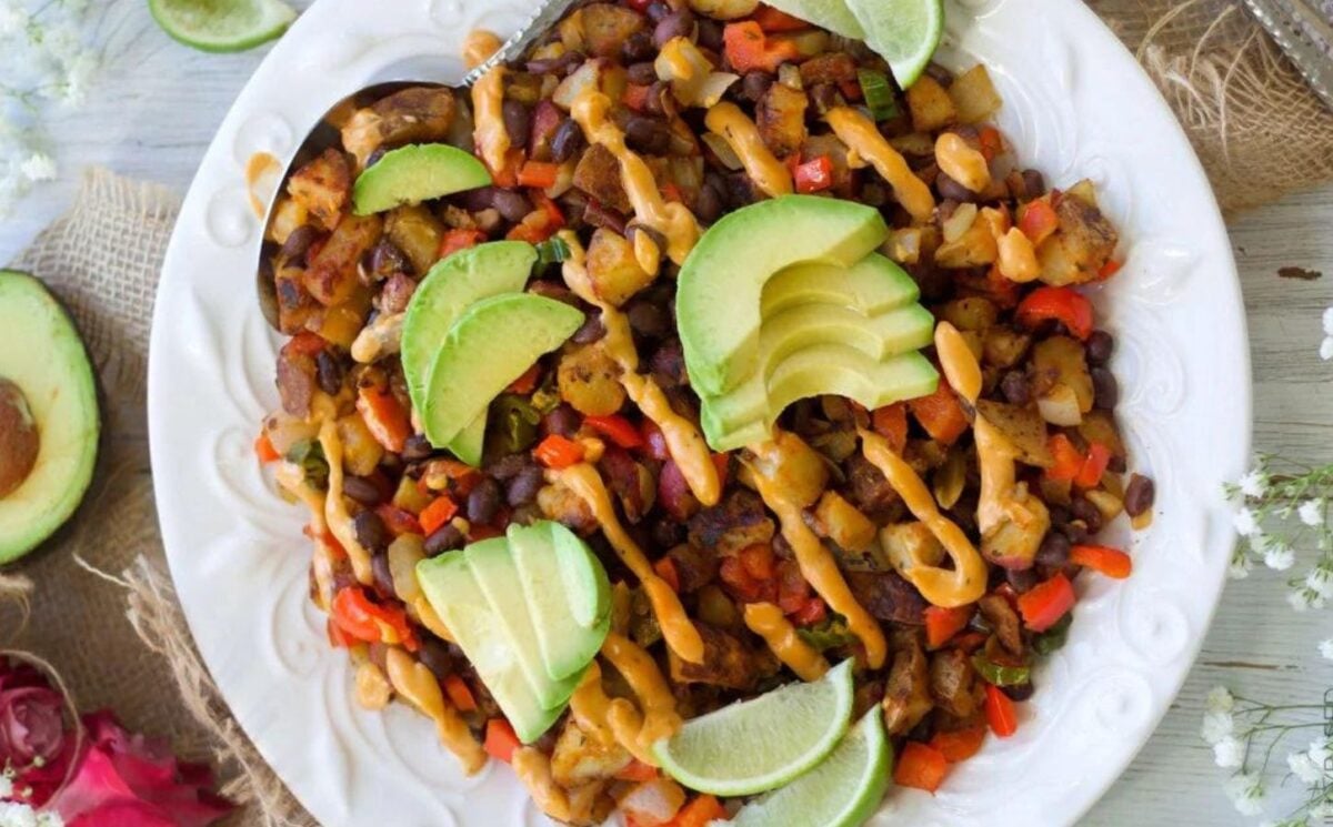 a picture of black bean breakfast hash topped with avocado, lime, and chipotle mayo sauce