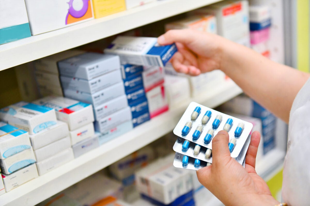 Photo shows a healthcare worker stocking shelves with medicines