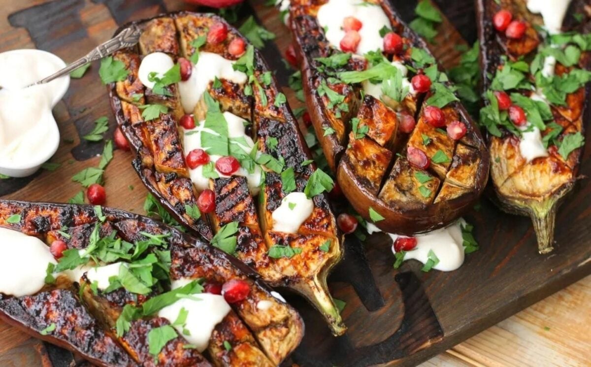 scored vegan miso aubergine steaks topped with parsley, pomegranate, and vegan yogurt