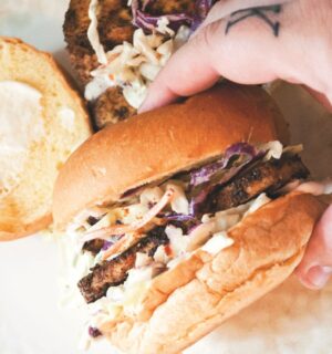 a picture of a hand holding a blackened tofu and coleslaw sandwich